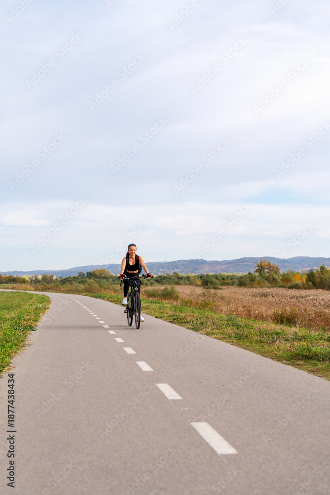 Obraz premium Active woman cycling on rural road in summer