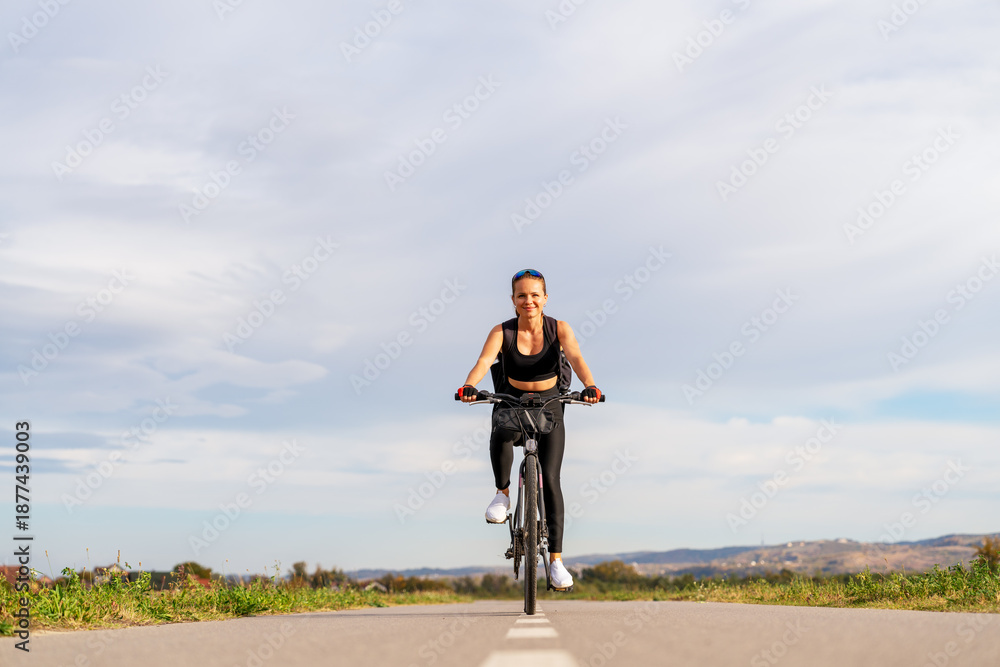 Obraz premium Female cyclist traveling through rural area in summer