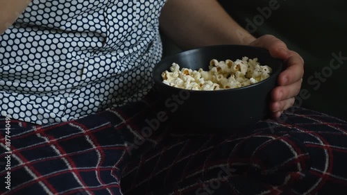 Woman picking popcorn from bowl. Close up