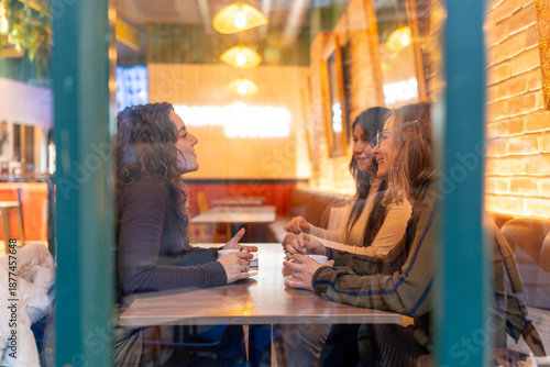 Canvas Print Women friends enjoying coffee and conversation in city cafe