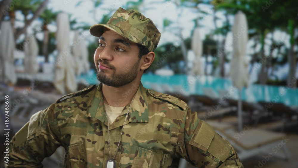 Fototapeta premium Man smirks with arms on hips by pool; confidence.