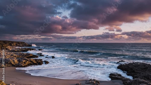 Rugged rocky shoreline with waves crashing against the shore at dusk with dramatic cloudy sky