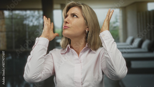 Free Download Woman holds head with both hands in spa studio lounge by poolside furniture clenching jaw amid loud noise; stress. - GFXLoad
