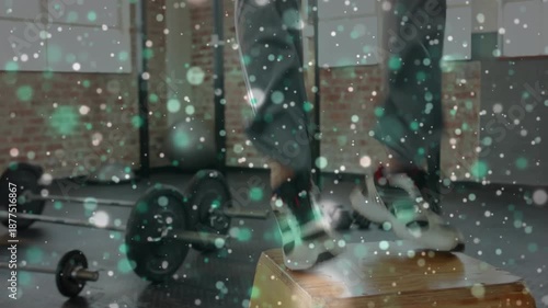 Animation of light spots over african american man exercising at gym