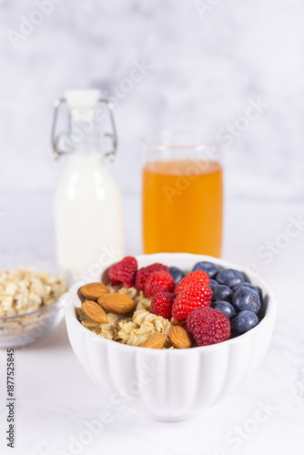 Healthy balanced breakfast with oatmeal, fresh berries, almonds, milk, juice and vegetables on marble background. 