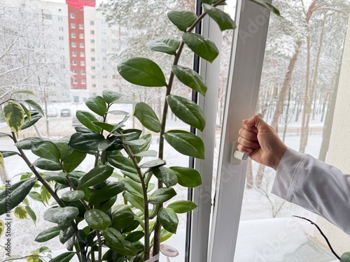 A woman opens a plastic window using the handle