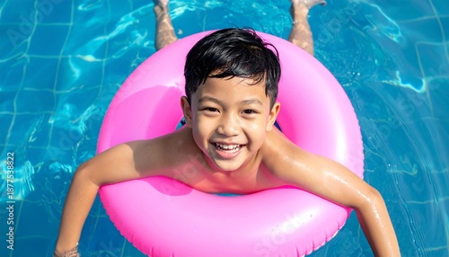 Happy Asian Boy Floating in a Pink Inflatable Ring in a Swimming Pool on a Sunny Day.