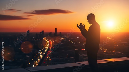 Silhouette of a man praying during vibrant city sunset
