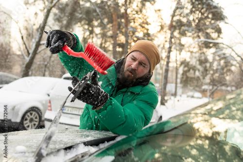 Man Clearing Snow from Car Windshield Wipers