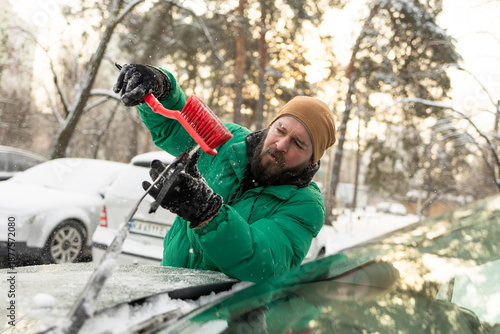 Man Tapping Snow off Car Wiper with Red Brush