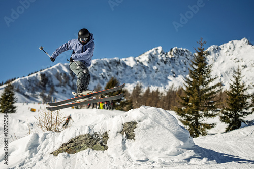 Fotografie skier performs a shifty trick on skis on a beautiful sunny day in the winter mountains