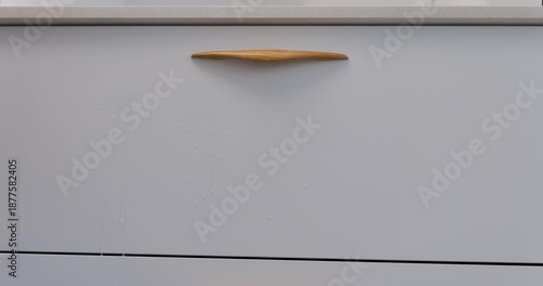 Woman cleaning kitchen cabinet fronts of modern furniture