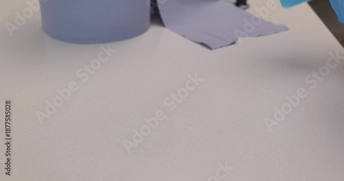 Woman cleaning stone kitchen countertop wearing protective gloves 