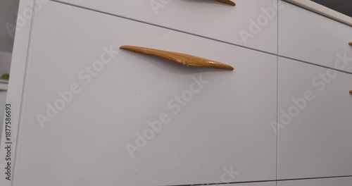 Woman cleaning kitchen cabinet fronts of modern furniture