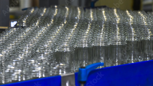 A conveyor belt with neat rows of glass jars