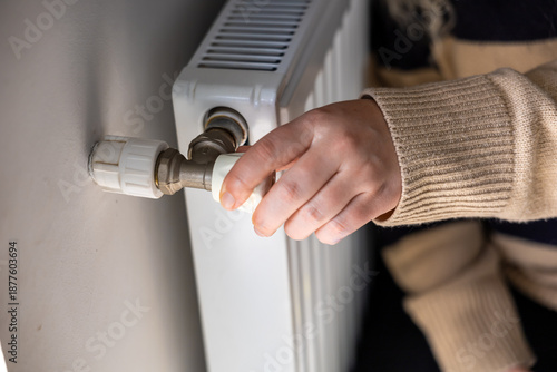 Obraz na plátně Regulation control of the heating temperature on the battery in the room, female hand