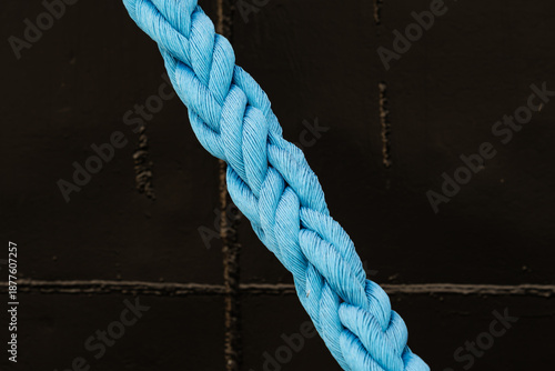 Foto Close up of a thick braided blue nylon mooring rope against a dark ship hull bac