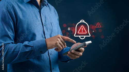 Emergency security notification concept with man holding smartphone displaying red alert bell icon for urgent system warning or danger message