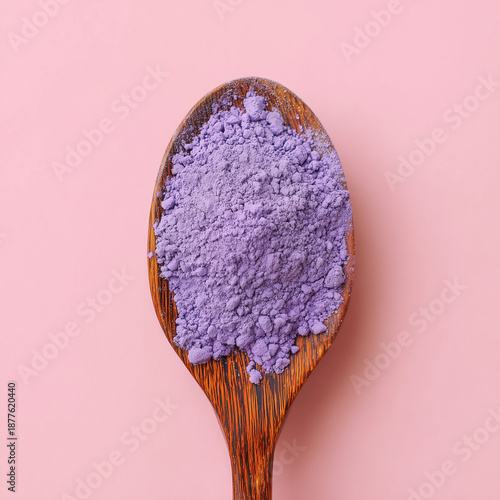 A spoon full of powdered  ube on a pink background