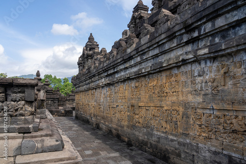 Scenic landscape view of gallery or corridor with stone bas-reliefs at UNESCO World Heritage Borobudur ancient buddhist temple, Magelang, Central Java, Indonesia