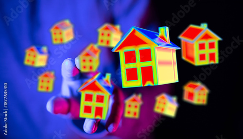 Photos Person's hand with miniature house models suggesting real estate investment and homeownership options