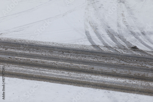 Abstract shot of tire tracks on snowy road surface during winter. Weather conditions, winter drivin