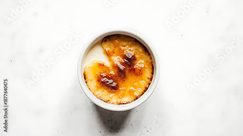 Top view of crème brûlée in white ramekin with caramelized sugar crust isolated on white background.

