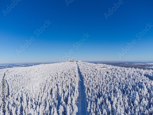 Winter panorama – Aerial view of a snow-covered mountain and mountain station peak under blue sky - Fichtelberg/Erzgebirge