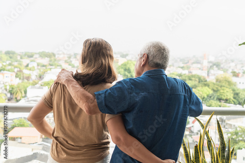 Senior couple embracing enjoying city view from balcony