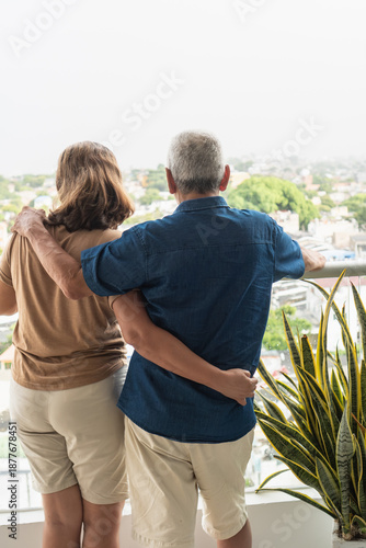 Senior couple embracing enjoying urban city view from balcony