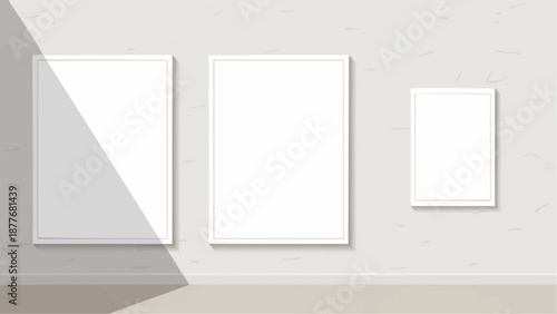 Three empty white picture frames on a light gray wall with shadows