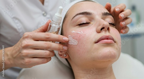 Woman receiving facial treatment in beauty salon. Cosmetologist applying cream to young woman face. Skincare procedure for healthy skin.