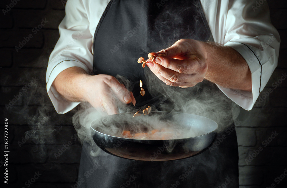 Obraz premium In the kitchen, a cook throws seeds into a frying pan. Steam rises from the pan as the cook concentrates on the cooking process. The kitchen is surrounded by a brick wall.