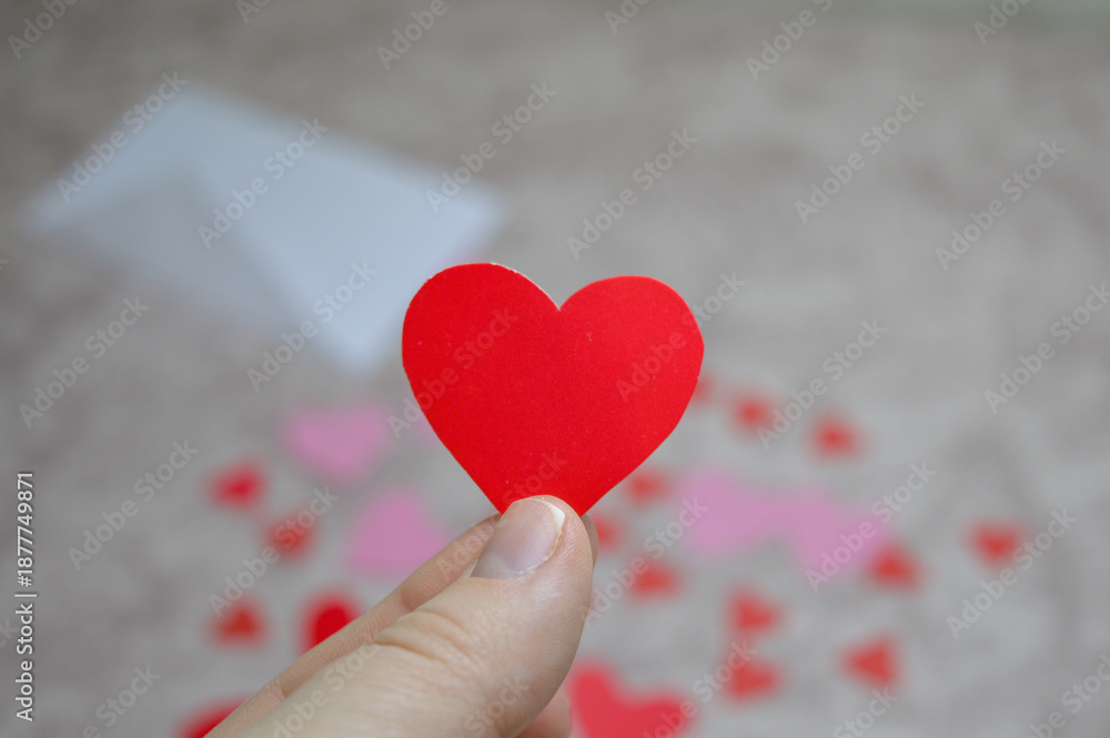 Fototapeta premium hand holding red paper heart with envelope and hearts in background, valentine’s day love message concept for romantic greeting cards, dating, relationships, wedding and holiday marketing