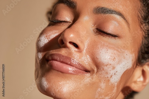 Calm self-care skincare shot: radiant woman applying foam cleanser with closed eyes