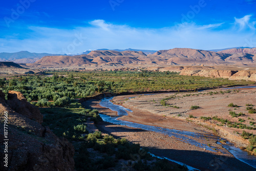 Vast desert landscape with a winding river and distant mountains under a clear blue sky. Ouarzazate, Morocco