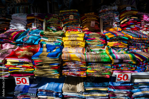 Colorful stacks of folded clothing arranged neatly with price signs in a vibrant marketplace. Rabat, Morocco