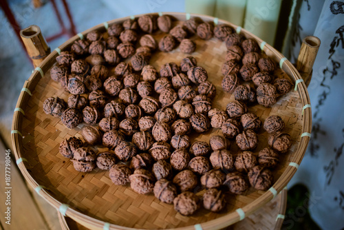 A woven basket filled with whole walnuts on a wooden surface. Chengdu, Sichuan, China