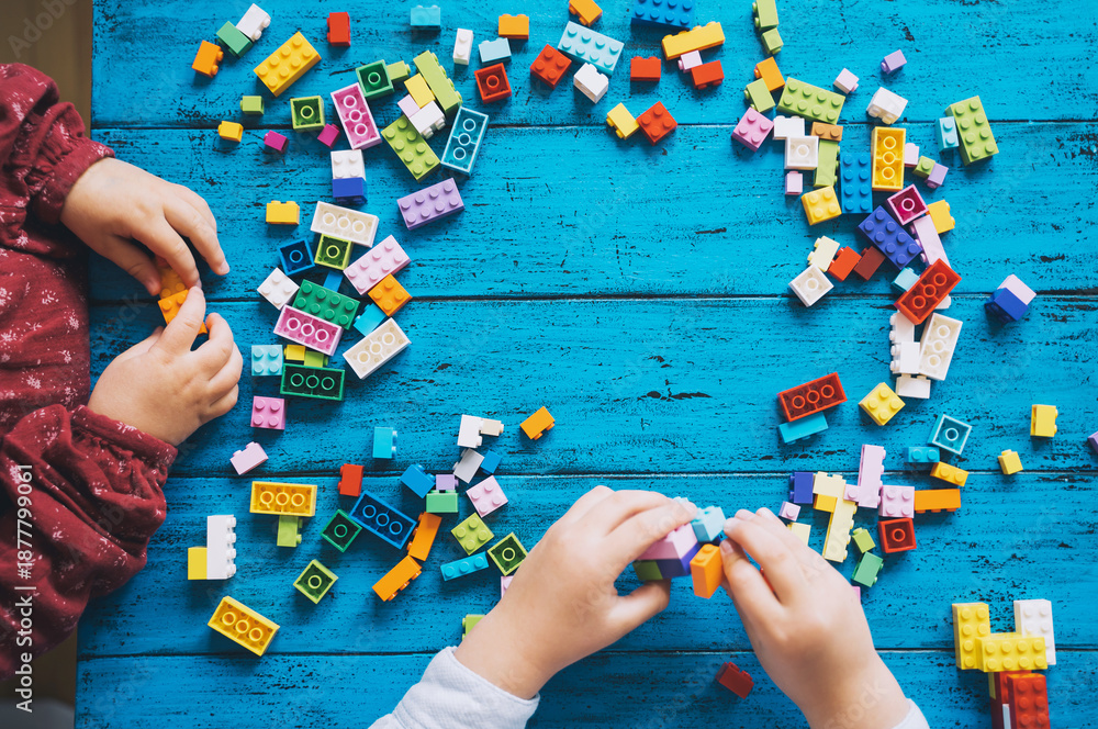 Fototapeta premium Children play and build with colorful toy bricks, plastic blocks.