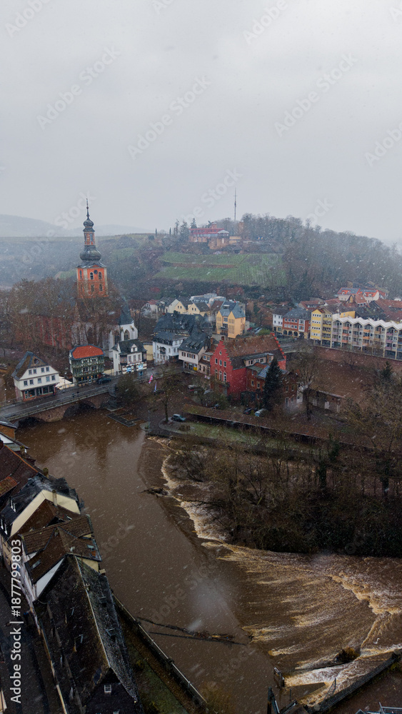 Fototapeta premium Breathtaking drone panorama of Bad Kreuznach's landmark bridge houses in winter. Traditional half-timbered facades reflected in the high water of the Nahe river at dusk.