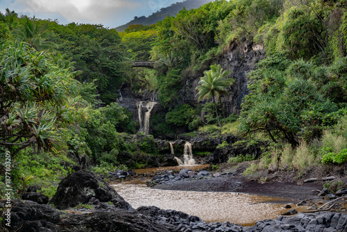 Lush tropical landscape with cascading waterfalls and a stone bridge over a rocky stream. Haiku, Hawaii, USA