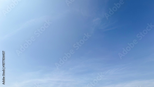 Fotografie A beautiful blue sky filled with soft white clouds on a bright sunny day