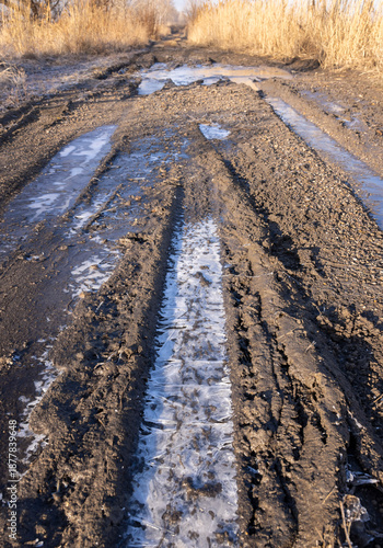 a dirt road in late autumn, covered with ice on a frosty morning
