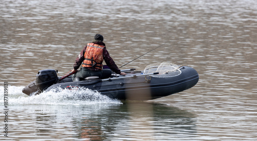 A fisherman in a rubber boat with a motor on the Irtysh River in Kazakhstan at the beginning of winter
