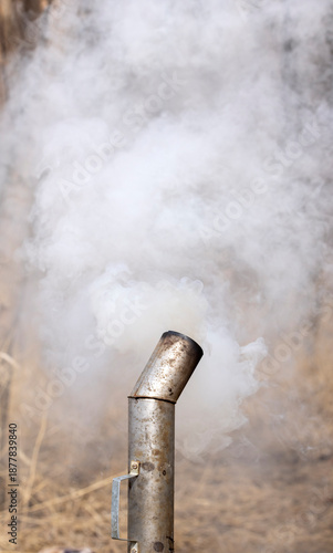 Thick white smoke from the chimney of a Russian samovar in the forest at a picnic
