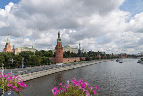 Moscow Kremlin towers and golden domes viewed from Moskva River, cloudy sky, flower beds in foreground