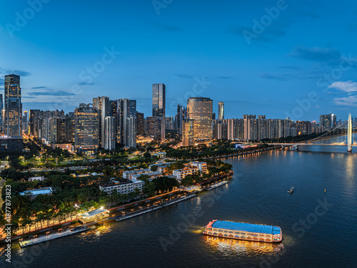 Vibrant illuminated modern city skyline and cruise boat on the Pearl River at dusk in Guangzhou, China.