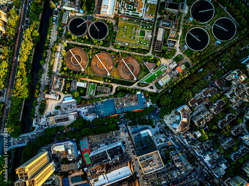 Aerial top-down view of a modern sewage treatment plant and water purification facility in a dense urban city area.