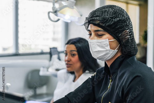 Dentist and female patient reviewing dental images on a computer screen during a professional consultation in a modern dental clinic.