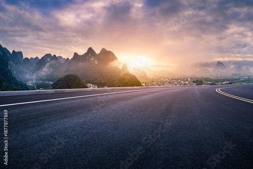 Majestic empty asphalt road leading towards karst mountains in Guilin, China during a beautiful sunset with dramatic clouds.